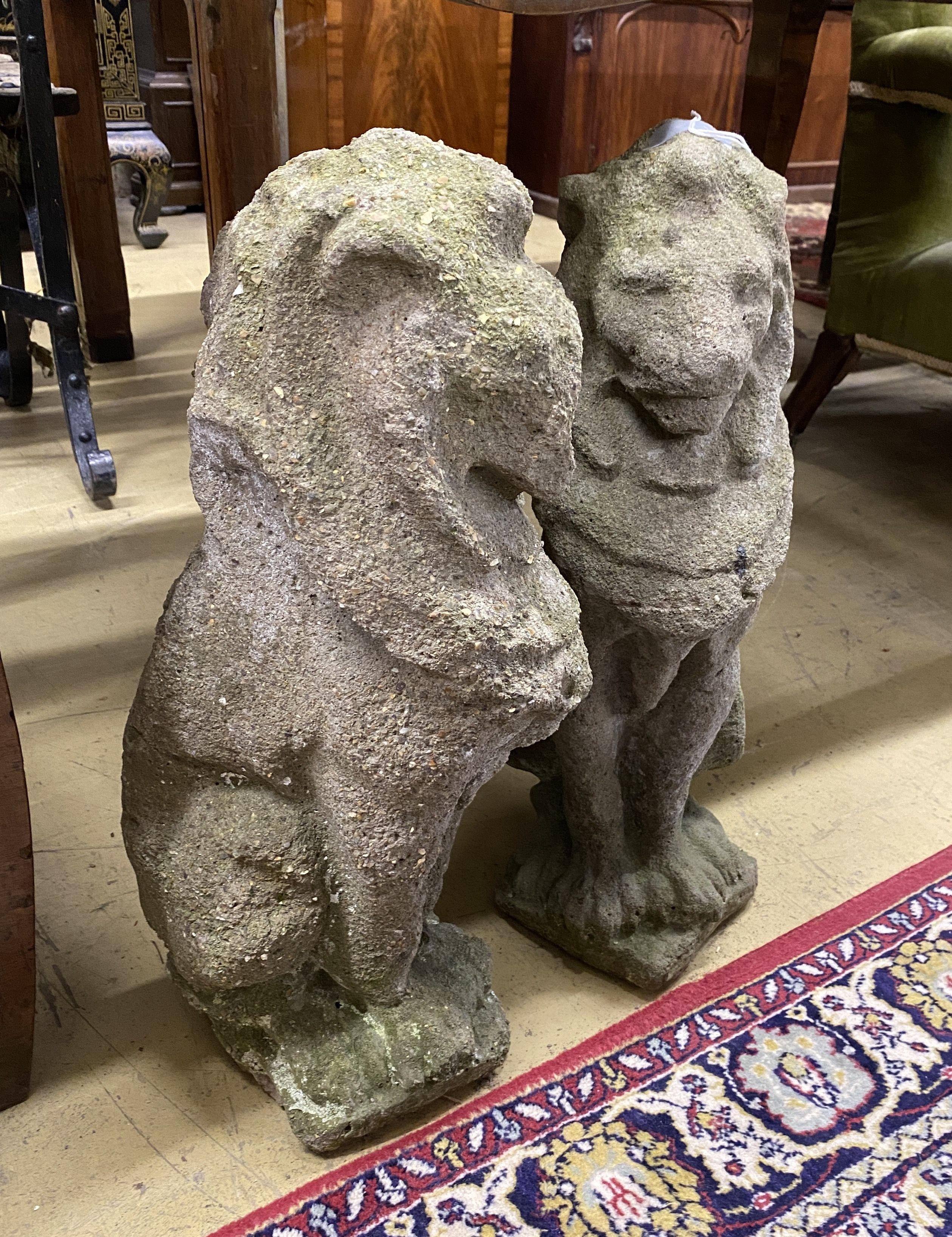 A pair of reconstituted stone seated lion garden ornaments, height 52cm